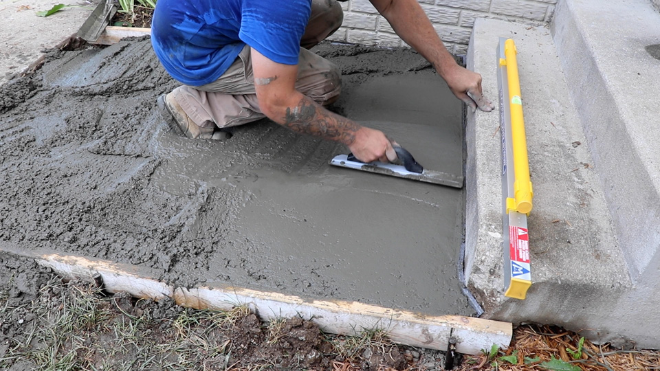 using a hand float to smooth concrete next to the stairs